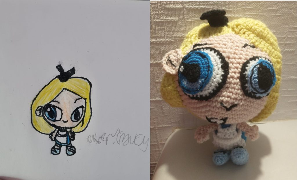 A photo showing a child's drawing of Alice in Wonderland on the left and the crochet toy on the right. Alice has a head much larger than her body with yellow hair parted in the middle with a black bow on top. She is wearing a blue dress with a white pinafore. She has very large blue eyes with black outlines and is wearing baby blue shoes.