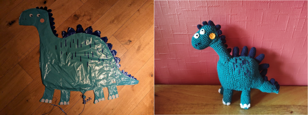 A photo showing a deflated balloon of a green stegosaurus type of dinosaur the left of the crochet toy version. It has blue spikes on its back and head and two white eyes on one side of its head and a round yellow spot on its cheek. It has some blue markings on its upper body and four white toes on each foot.