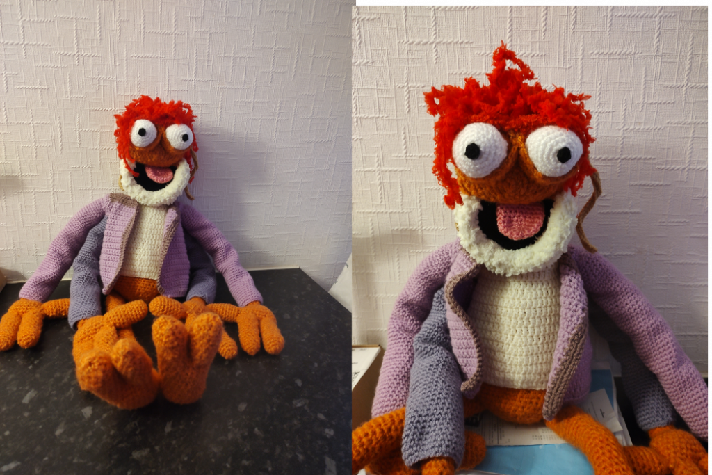 Two photos of a crochet version of the muppet Pepe the King Prawn sitting on a black surface. The second is a zoomed in version of the first showing his bug muppet mouth smiling. He is wearing a cream jumper and a purple jacket, but no trousers. He has two orange legs and four arms and he has big bulging white eyes and a mop of red "hair" on his head.