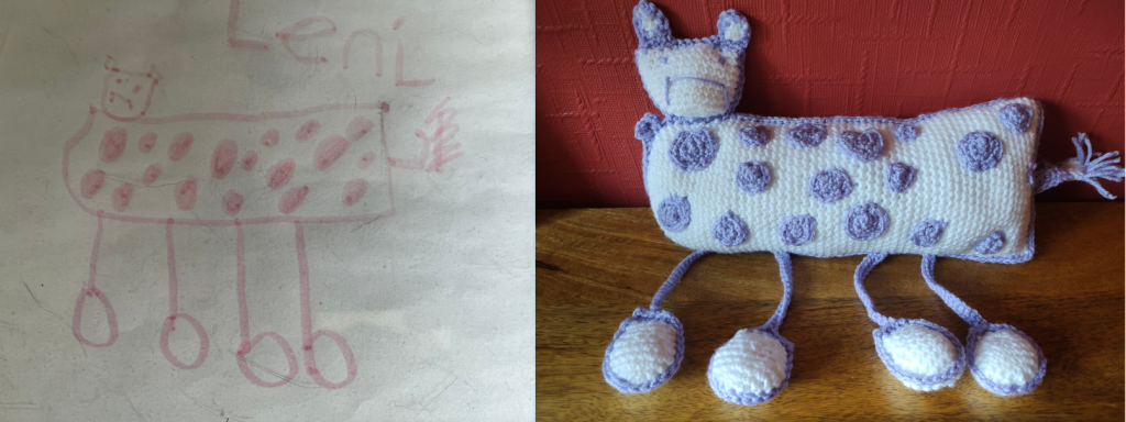 A child's drawing showing a white creature with purple spots on it and thin little purple legs with big round white feet. Next to it is the crochet toy of the drawing