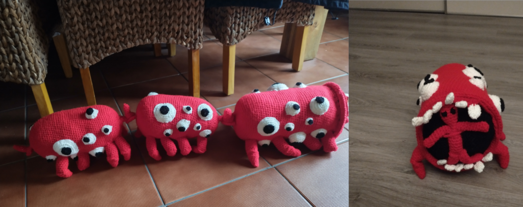 A crochet toy of a train eater, which is a creepy red train with multiple legs per carriage that is covered in white bulging eyes with black pupils. This one has three carriages shown on the left and on the right the front of the drivers carriage showing a black mouth with ragged white teeth and a red figure with black eyes inside it.