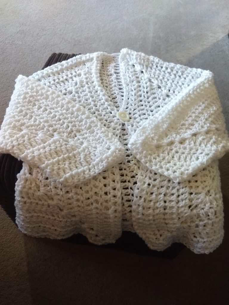 A crochet cardigan in white made from two crochet granny square hexagons
