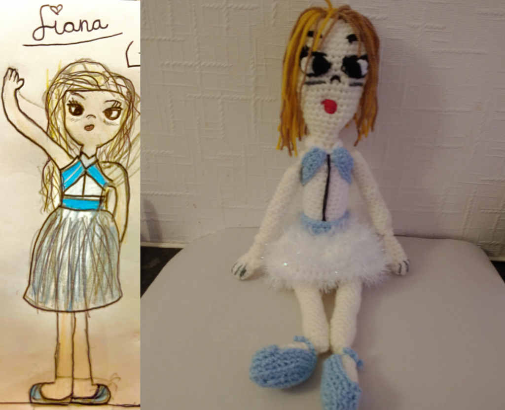 A drawing of a ballerina wearing a blue cross over top and a white tutu and blue ballet shoes. She has dirty blonde hair and a big eyes. The crochet doll is on the right sporting a sparkly white tutu