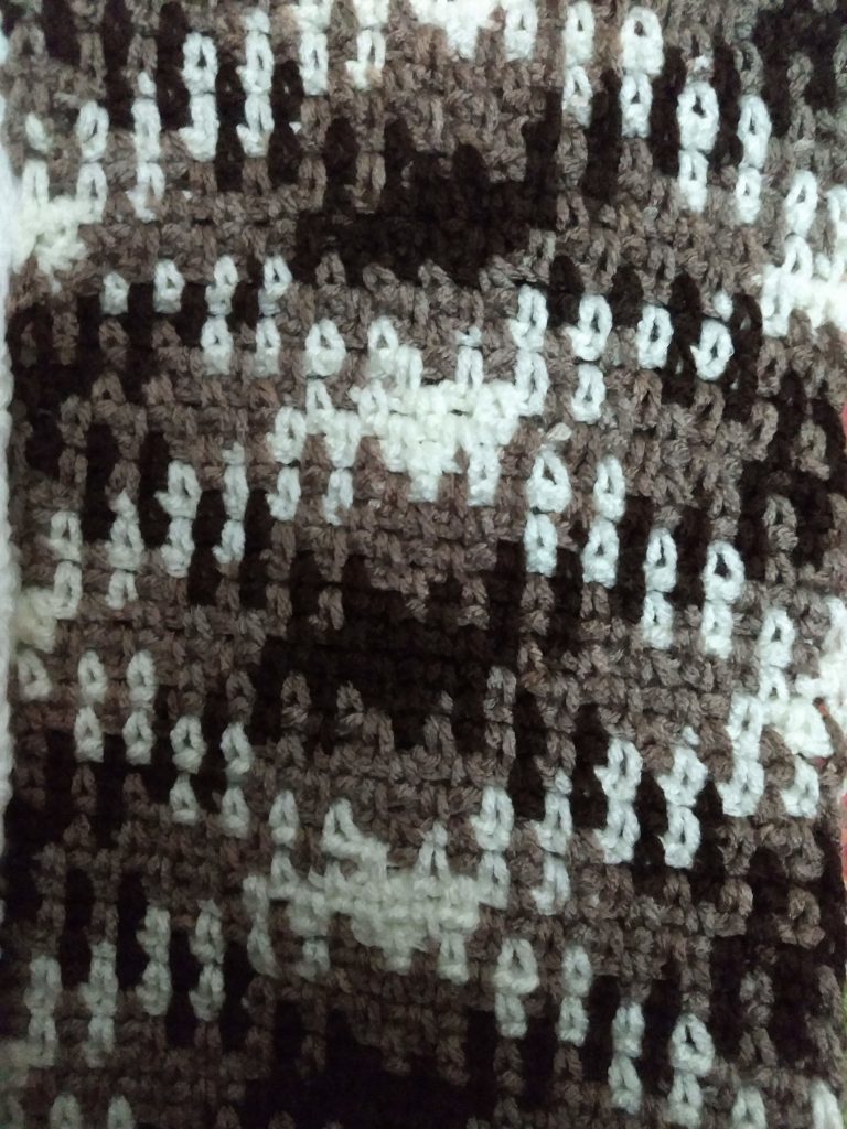 A close up of a crochet piece in the Argyle pattern in shades of brown and cream