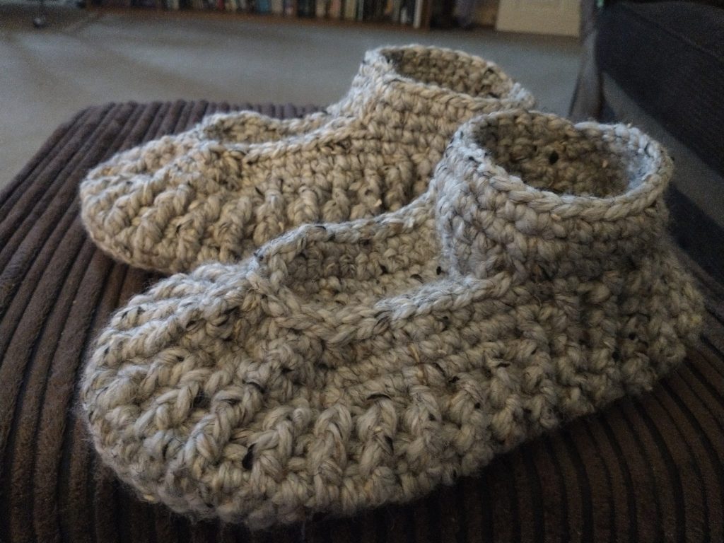 A pair of men's chunky slippers made with a speckled beige yarn