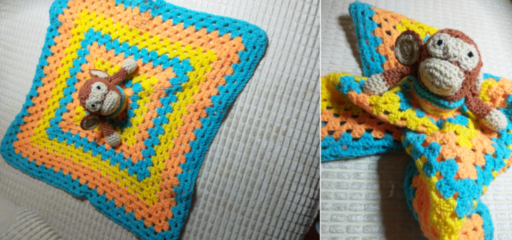 A crochet "lovely" blanket for a baby worked in alternating blue, orange and yellow granny squares with a little brown crochet monkey in the middle