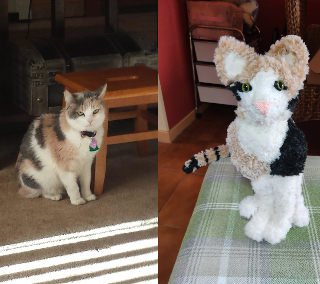 A photo of a calico cat on the left with a crochet toy version of the cat on the right. The crochet toy version has been made from very fluffy yarn and is looking directly at the camera with a white face, green eyes and large fluffy brown ears.